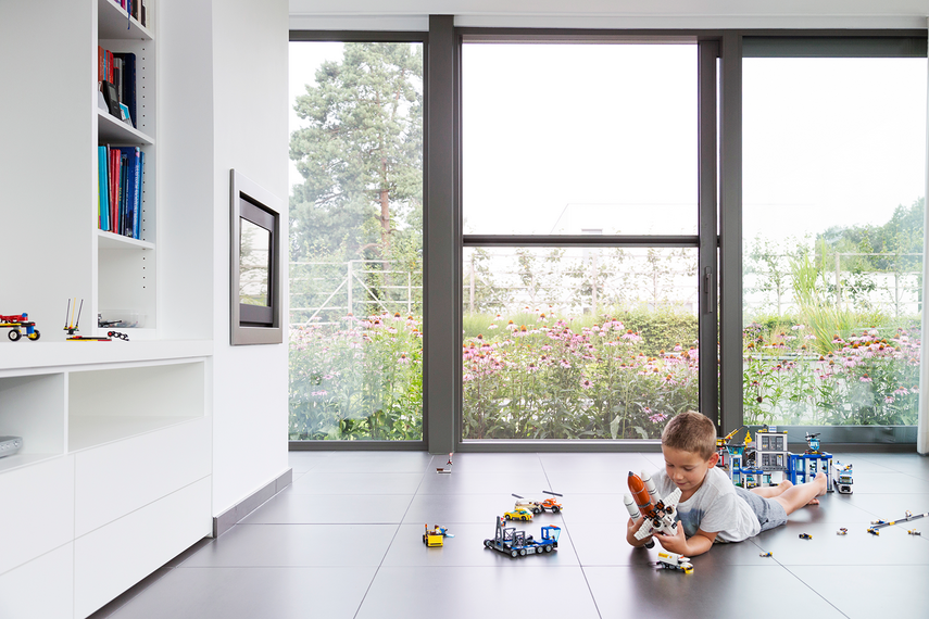 Kind ligt te spelen voor open schuifraam met vliegendeur