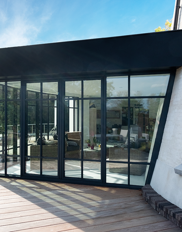 Zwarte leefveranda aan witte molenwoning