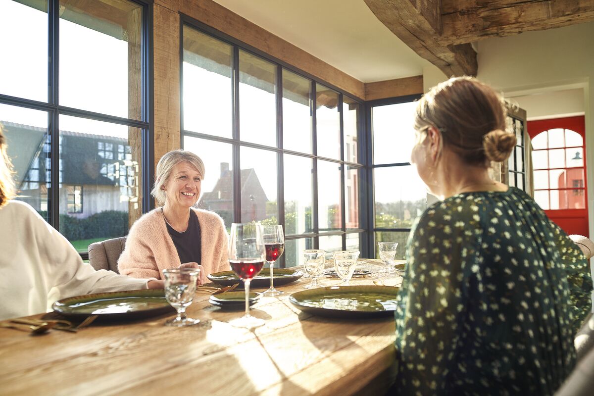 Mensen aan tafel in een woning met steellook aluminium ramen