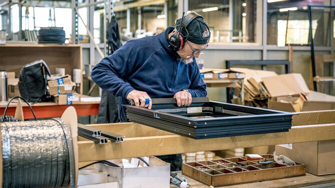 Man is een zwart aluminium raam van Reynaers Aluminium aan het monteren