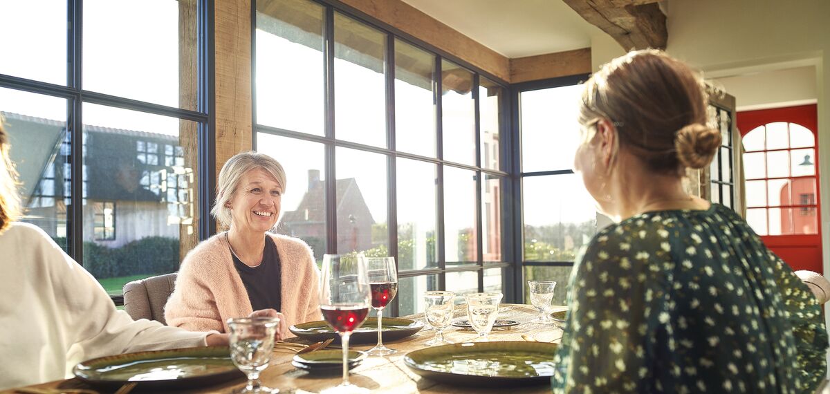 Mensen aan tafel in een woning met steellook aluminium ramen