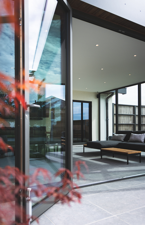 Leefveranda met loungeset gezien door openstaande glazen vouwdeur