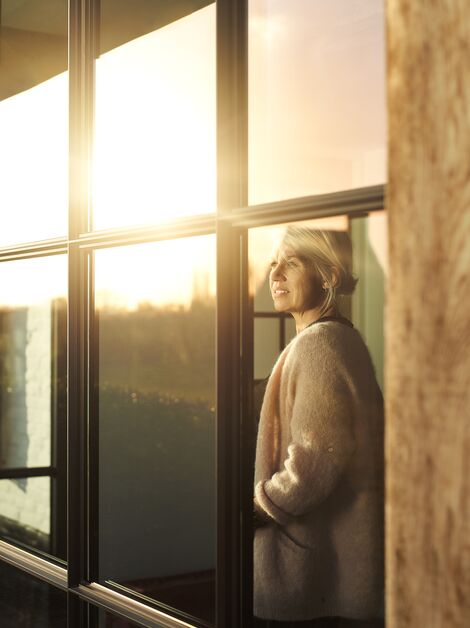 Vrouw in het zonlicht achter aluminium raam