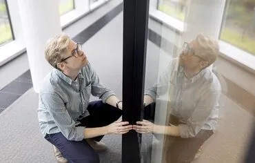 Homme avec des lunettes tenant un profil en aluminium noir.